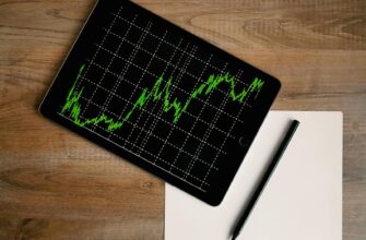 Flatlay of an iPad displaying stock market graph on a wooden desk with a pencil and paper.