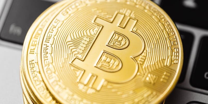 Close-up of golden Bitcoin coins stacked on a laptop keyboard showcasing cryptocurrency and finance concepts.