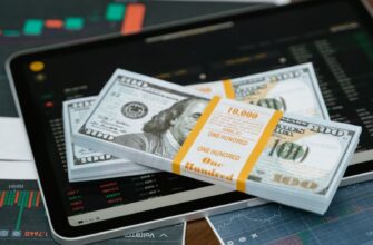 Stack of $100 bills placed on a tablet with financial graphs, symbolizing digital finance.