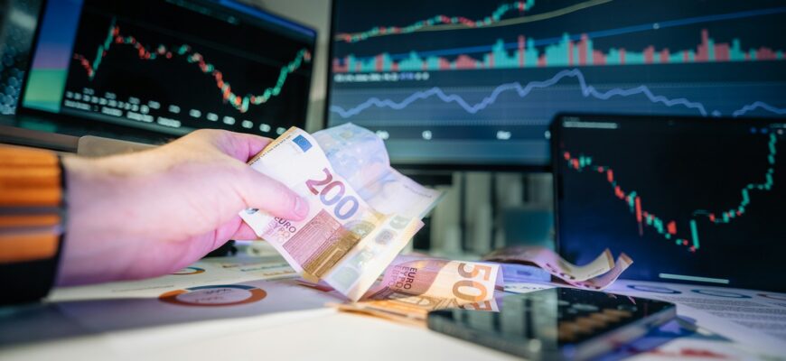 A person holding money in front of a computer screen