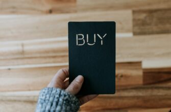 a person holding a black book with the word buy written on it