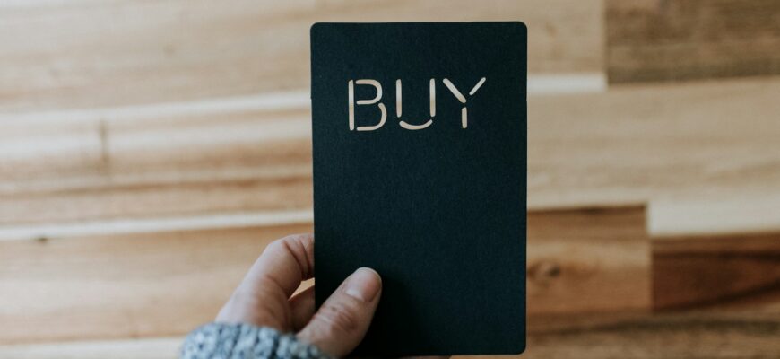 a person holding a black book with the word buy written on it